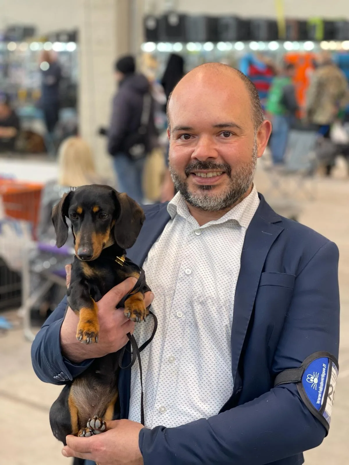 Michele, dog trainer and partner of LA BANDA BASSOTTO, holding a black and tan dachshund at a dog show
